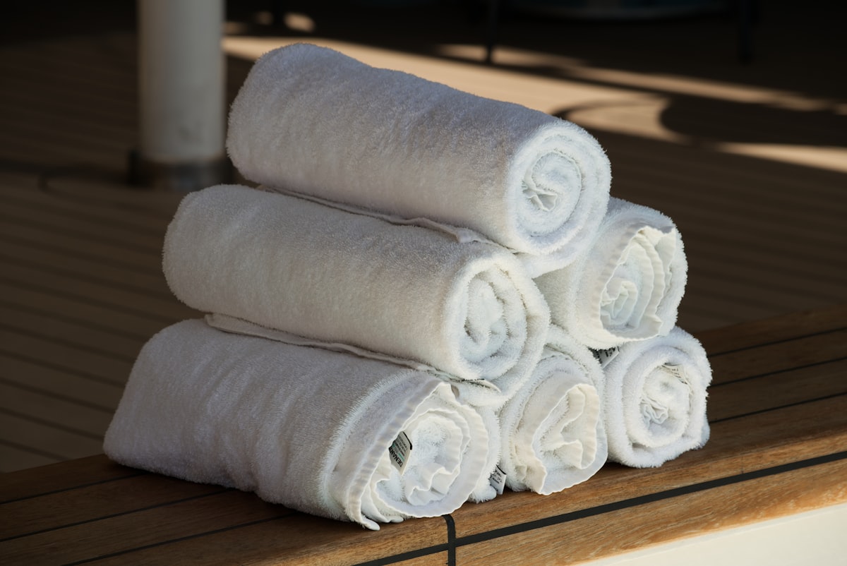 Freshly rolled white towels stacked on warm wood